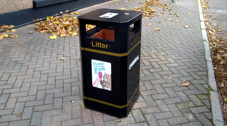 Photo of a public litter bin in Irby featuring a poster promoting the chewing gum clean-up campaign