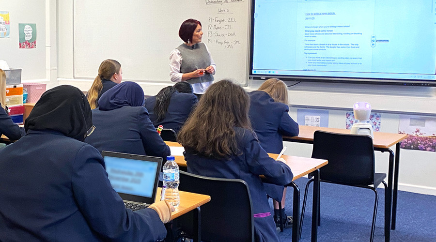 AV1 robot on desk in classroom surrounded by other students and teacher