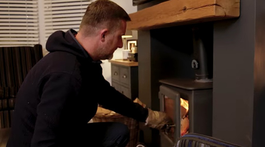 Man closing the door of his log-burner in his living room