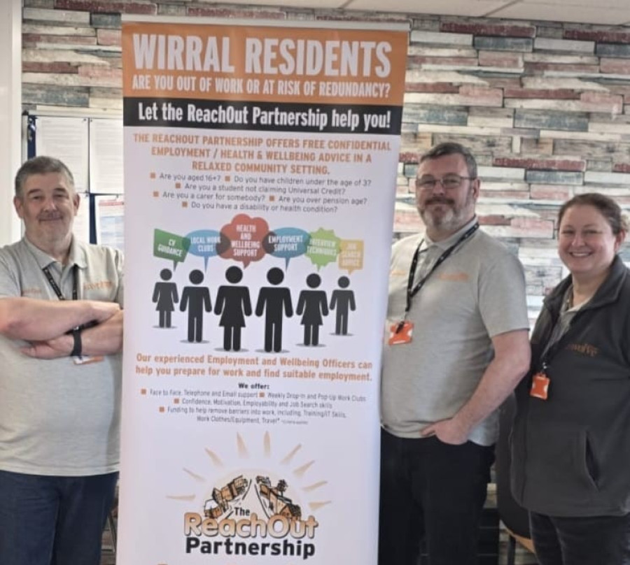 Three members of the ReachOut team stand in front of a pop up ReachOut poster at a community event