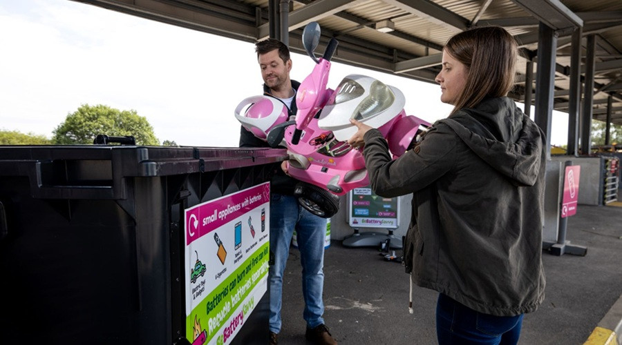 A stock image of a dad and daughter disposing of old toys at their local recycling centre