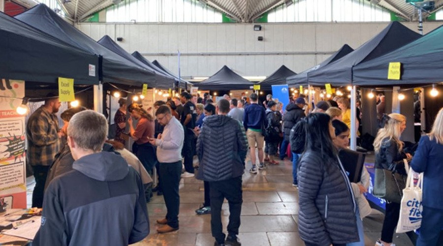 Lots of people shown browsing stalls at a jobs fair in Birkenhead Market