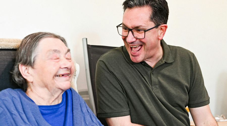 2 men smiling, one is elderly and the other is younger