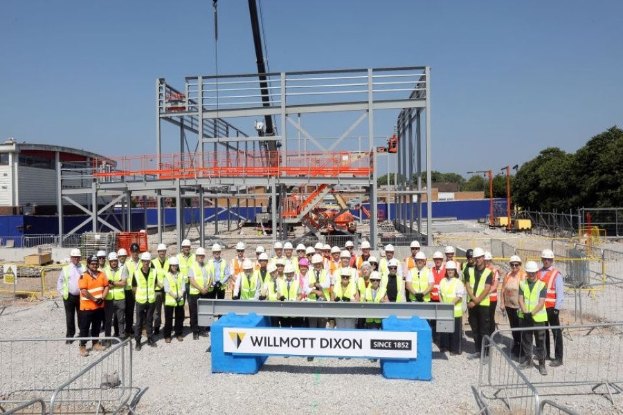 A group of contractors, councillors, teachers and students stand outside the new steel frame of the new Mosslands School