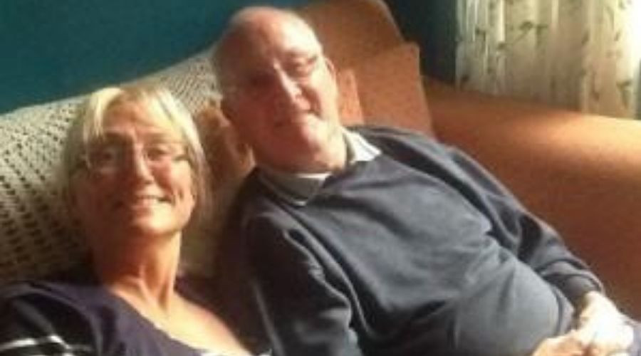 Man and woman sitting on the couch smiling at the camera