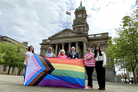Wirral Council staff with a rainbow progress flag outside Birkenhead Town Hall