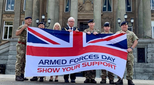 The Mayor and Mayoress holding the Armes Forces Day flag with local soldiers