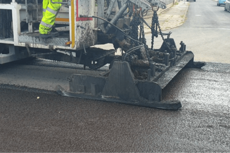Machinery working on a road, applying a microasphalt treatment in Wirral