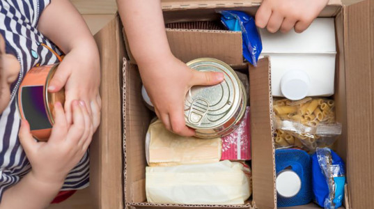 Stock image of food items being packed in a cardboard box