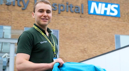 NHS Apprentice young man looking ahead in front of a hospital