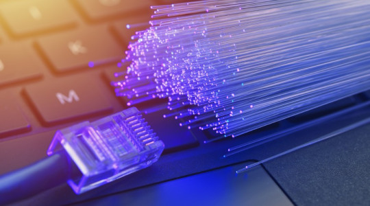 Stock image depicting broadband internet - illustrating a computer keyboard, LAN connector and fibre connectors
