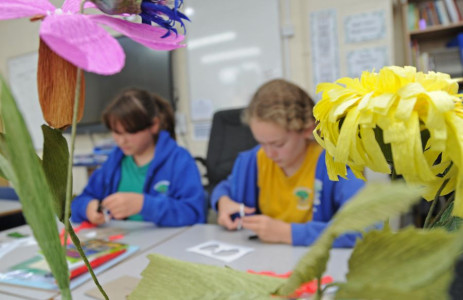 Paper flowers in the foreground with children in the background making more paper flowers