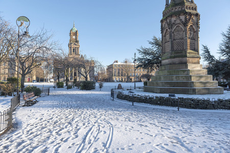 Hamilton Square and gardens covered in snow with some footprints in the snow on the path. 