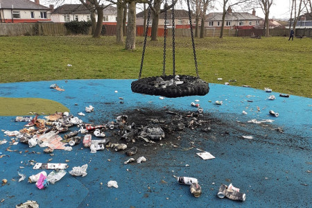 image shows a burned out tyre swing with rubbish and debris around