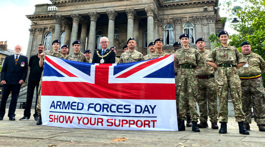 A group of people including The Mayor of Wirral, Army Reserves, Army Cadets and civilians holding Armed Forces Day flag in front of Birkenhead Town Hall