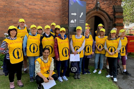 Group photo of The Open's volunteer ambassadors in Hoylake wearing yellow bibs and baseball caps 