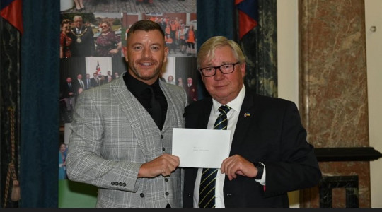 Photo of Matt Tomlinson of Rek 41 receiving a donation from former Mayor, Cllr Jeff Green