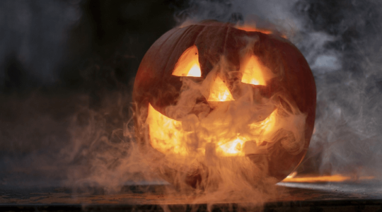 A carved pumpkin with smoke around it