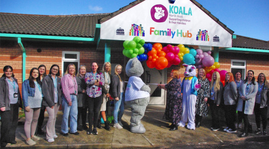 Group of people stand outside Koala North West family hub with balloons