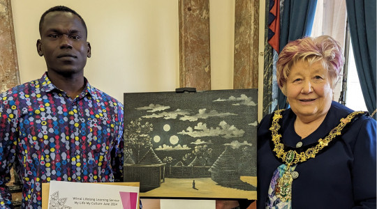 A student stands next to the Mayor, in between them is a piece of art