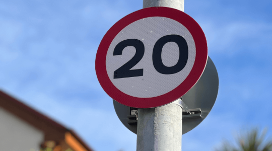 Close up of a reminder 20mph roundel sign - a white sign with a red outer ring and the number '20' in black