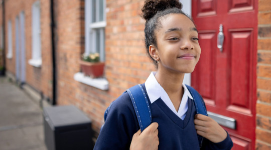 Photo of a smiling school student in front of a red door