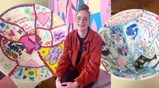 two broken bowls, mended with glittery glue in the cracks and covered in inspirational words and pictures sit either side of emma who is smiling to camera