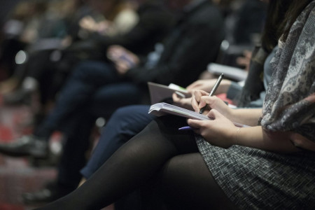 A row of people sat on chairs listening to a presentation