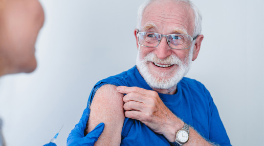 Older man pulling up sleeve preparing for injection and smiling