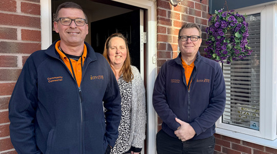 three people standing in front of an open door smiling