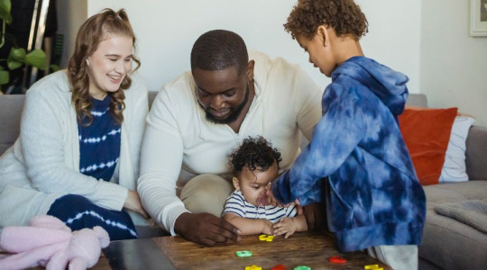 A family of 2 adults and 2 children playing with a puzzle