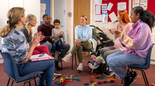 Parents, carers and grandparents sat around in a play session with discussion