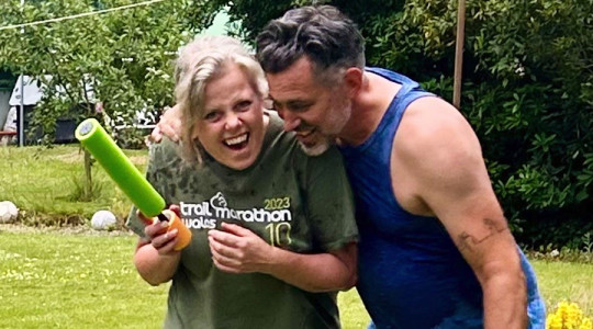 Foster carers having fun being soaked by foster kids playing in a water gun fight