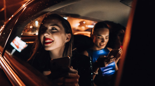 Two girls in the back of a private hire taxi after a night out