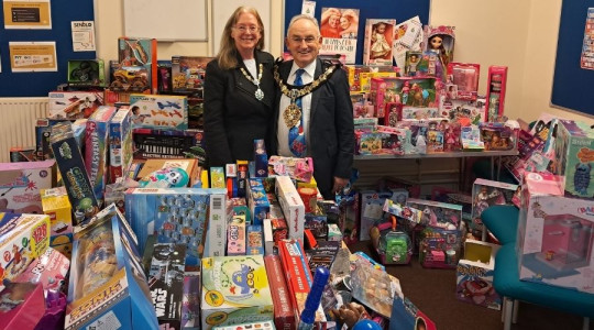 Photo of the Mayoress and Mayor surrounded by hundreds of gifts that were donated