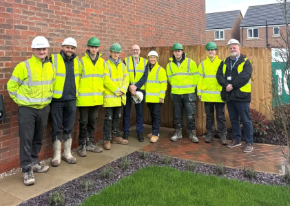 Persimmon site staff, apprentices and representatives from Wirral Council and Wirral Met College stand outside a building on the River Walk development wearing high vis jackets