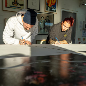 Artists SNIK drawing mural leaning on table
