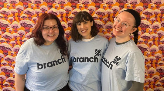 Three women stand posing and smiling for a group photo