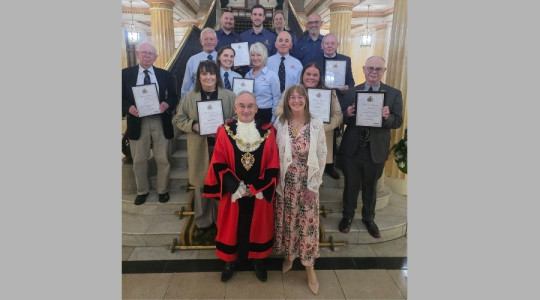 Photo of the mayor and Mayoress of Wirral on a grand staircase in Wallasey town hall with the recipients of the Wirral Award holding their certificates of appreciation