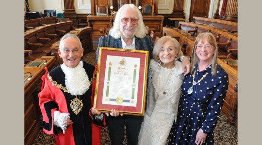 Photo of Charlie holding his scroll in the Council Chamber 