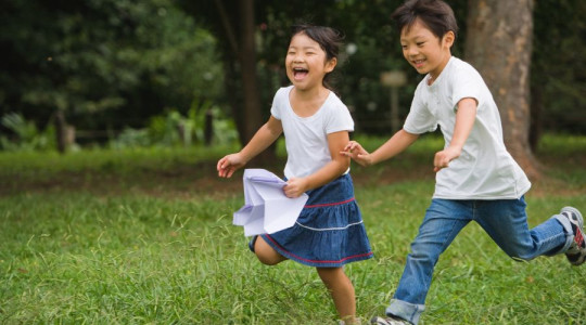 two children running and laughing in a park