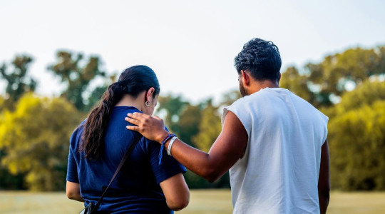 Man placing a hand on a woman's shoulder in a comforting way