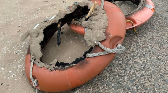 Fire-damaged life rings left behind on a beach in Wirral after being vandalised