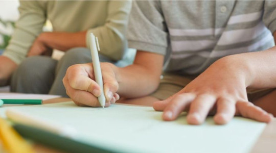 child writing in notebook