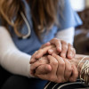 Close up image of a younger and older person holding hands