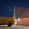 A yellow gritting vehicle parked alongside the salt dome ready to be loaded with salt.