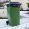 Green wheelie bin surrounded by snow 