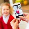 Little girl aged around 4 years old poses for a photograph from her mother in her new school uniform. 