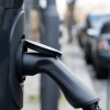 Close up of an eletric vehicle charging point plugged in and attached to a car that's on the street