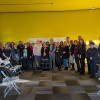 A group of men and women standing in a row in front of a yellow wall